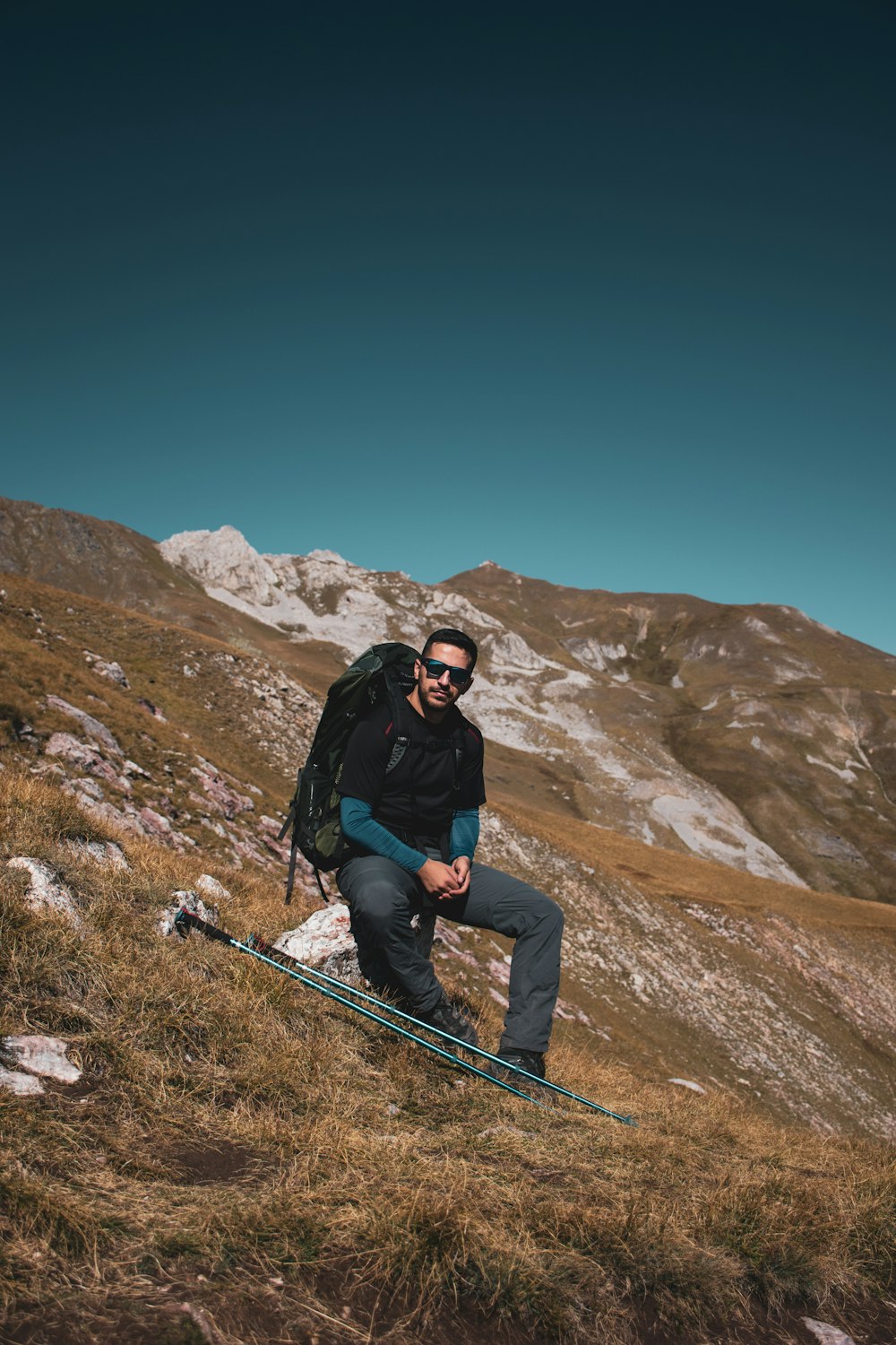 Ein Mann sitzt mit einem Rucksack auf einem Berg