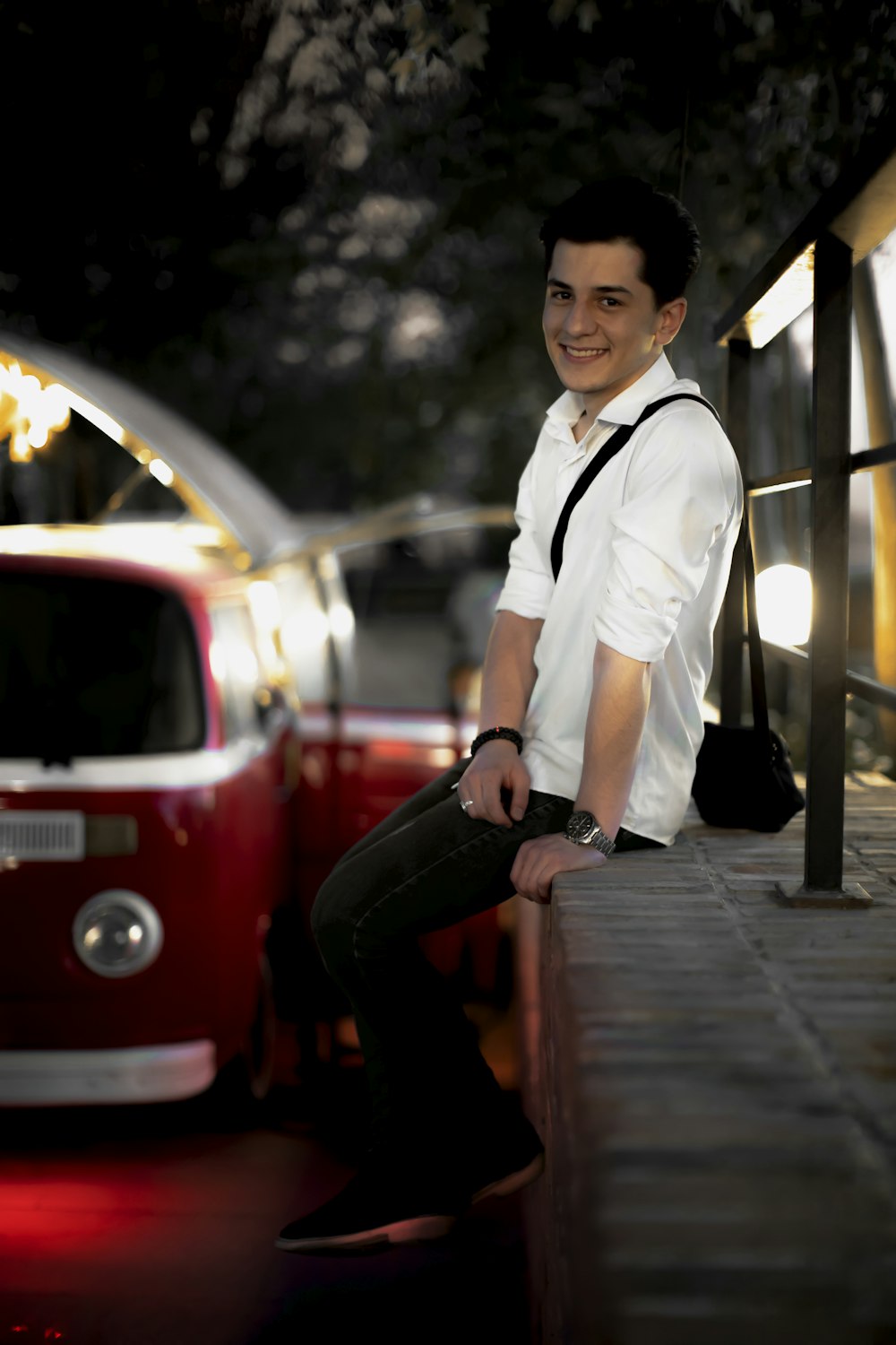 a man sitting on a ledge next to a red bus