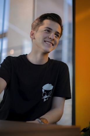 A young boy smiling after a fresh haircut at Dani Molina Hair Studio with black and white decor in the background.