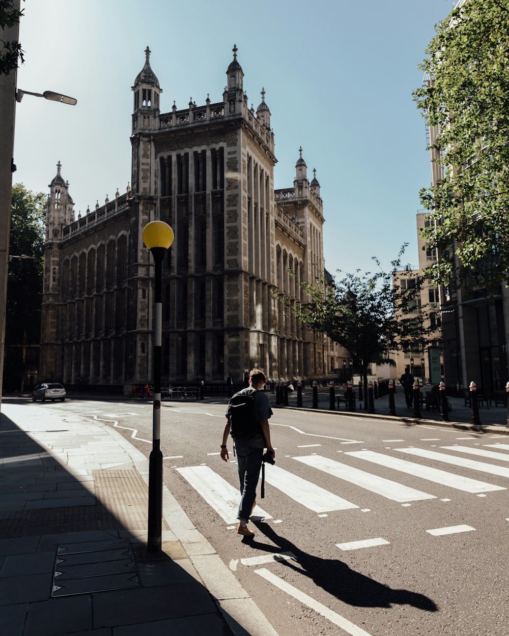 a man walking across a street next to a tall building