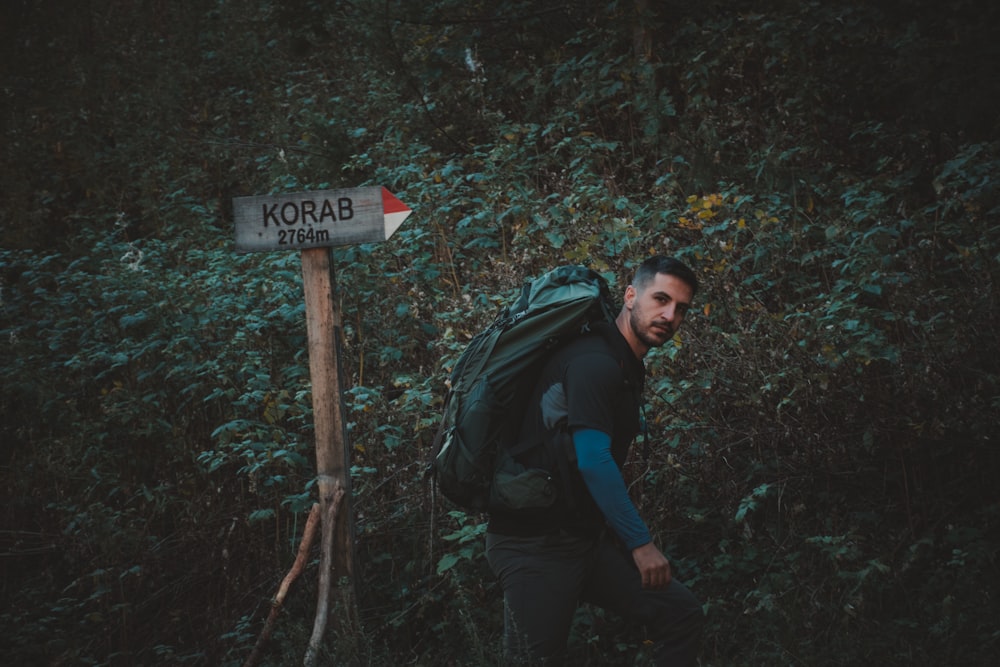 a man with a backpack is walking towards a sign