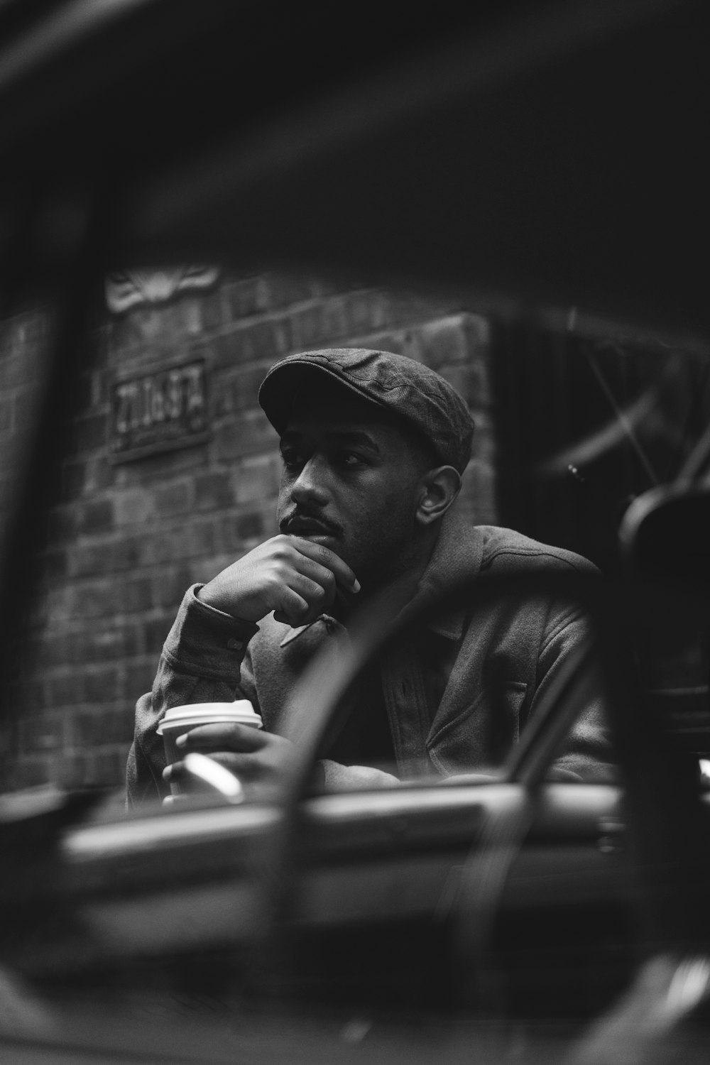 a black and white photo of a man sitting in a car