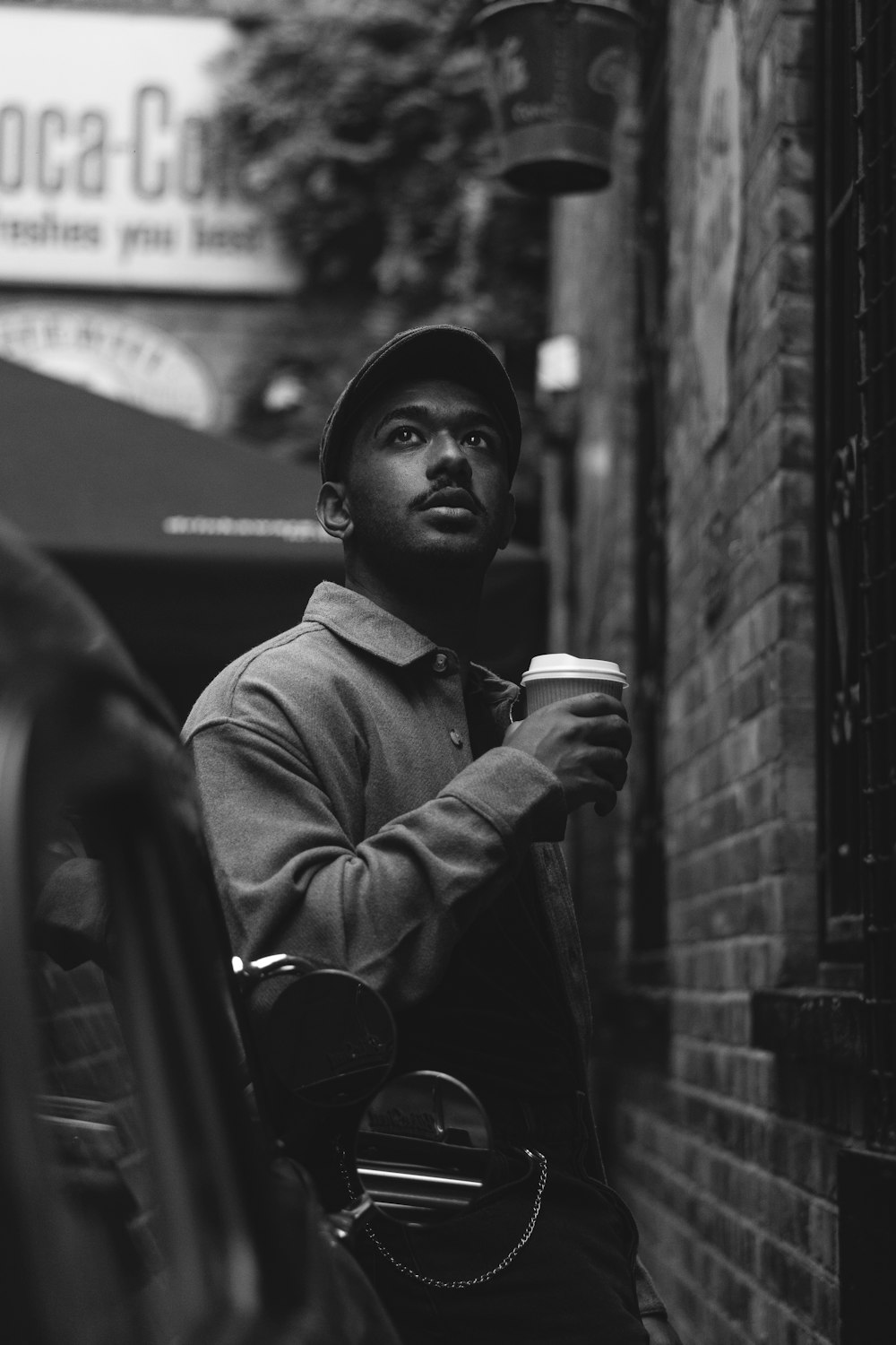 a man holding a cup of coffee while standing next to a brick building