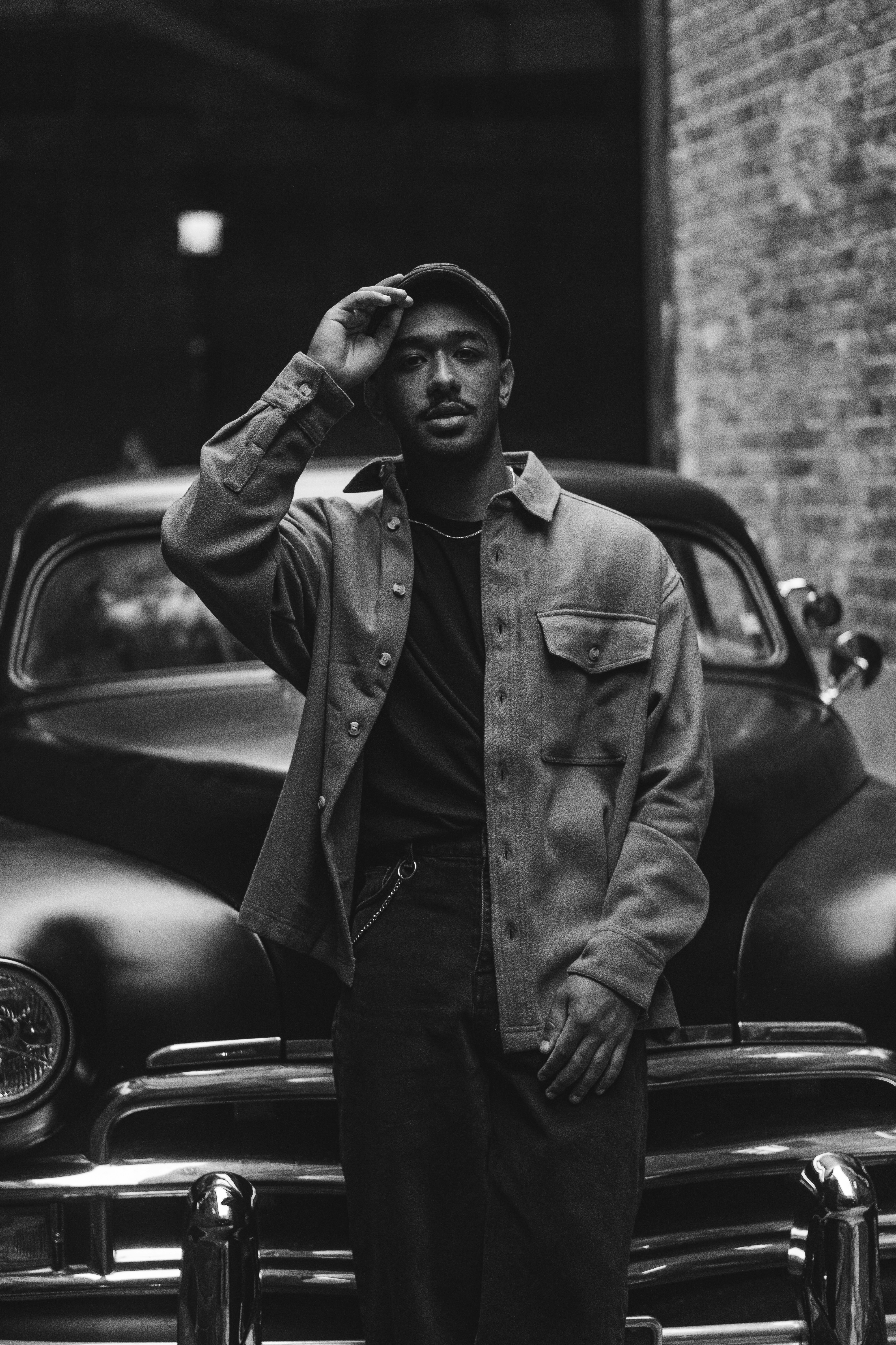 a black and white photo of a man standing in front of a car
