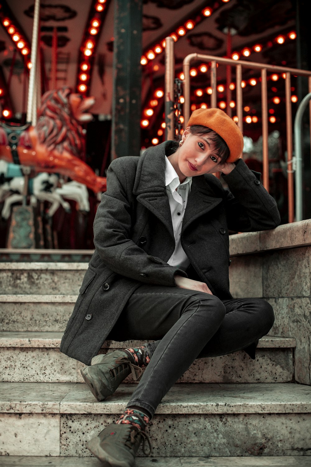 a young man sitting on the steps of a carousel