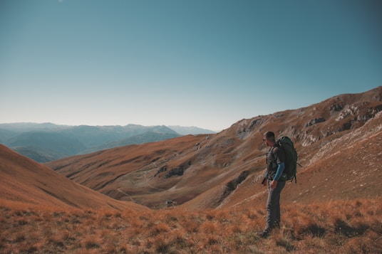 a photo of a man with a backpack standing on a hill