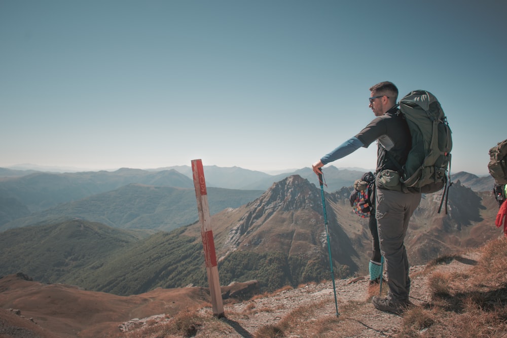 Un uomo in piedi sulla cima di una montagna con uno zaino