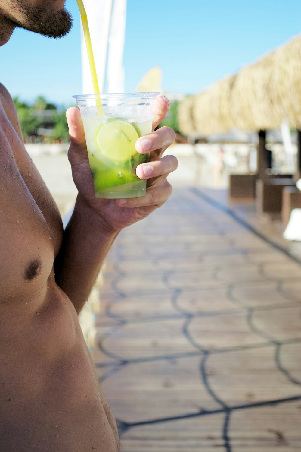 a shirtless man holding a drink in his hand