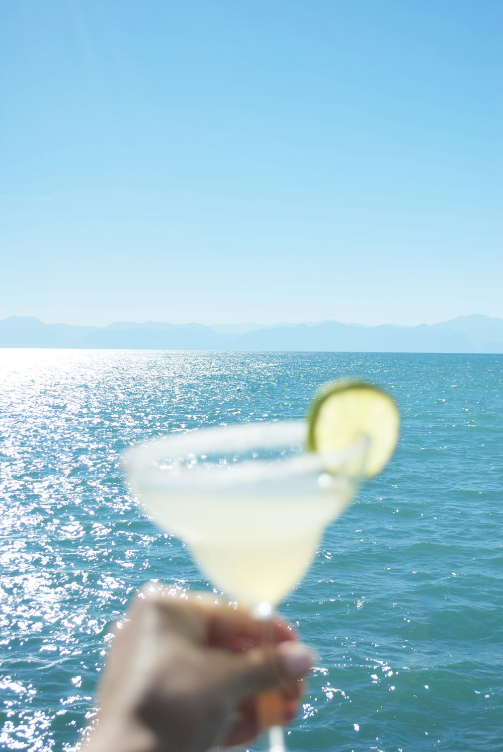 a person holding a martini glass with a lime slice on it