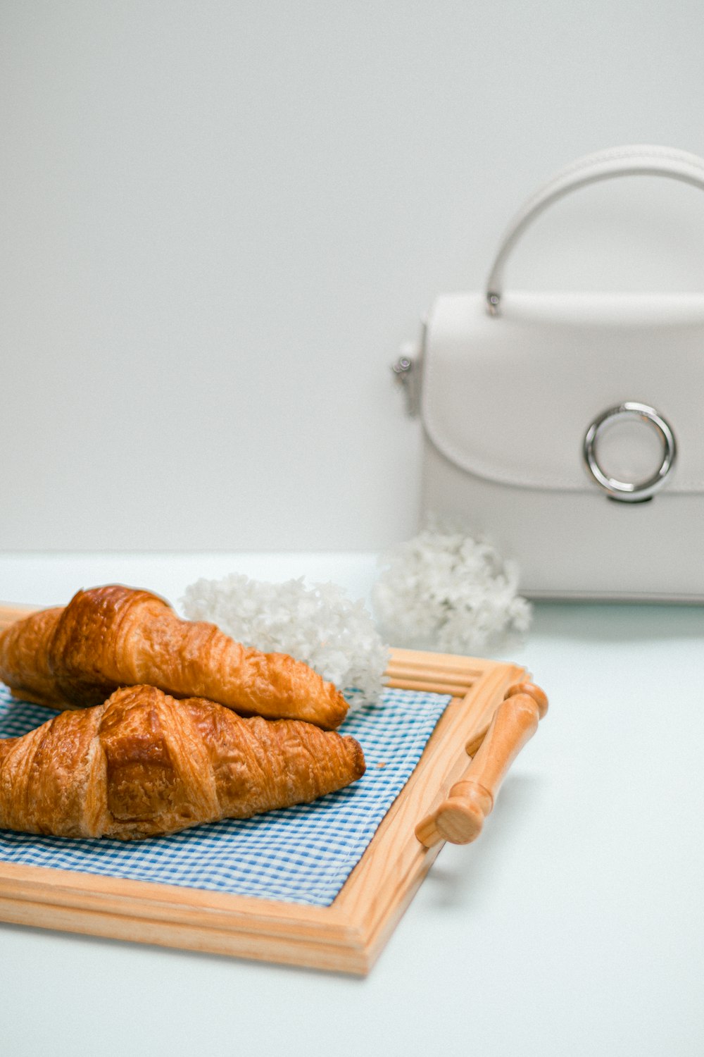 two croissants on a blue mat next to a white purse