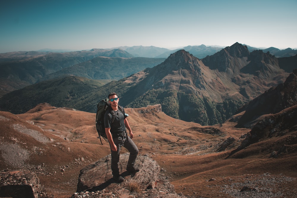 Un uomo con uno zaino in piedi sulla cima di una montagna