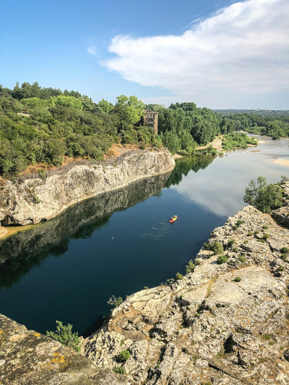 a small boat on a river near a cliff