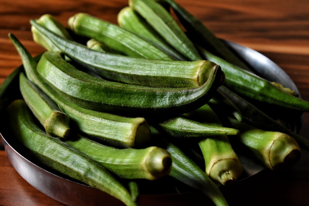 un bol en métal rempli de haricots verts sur une table en bois