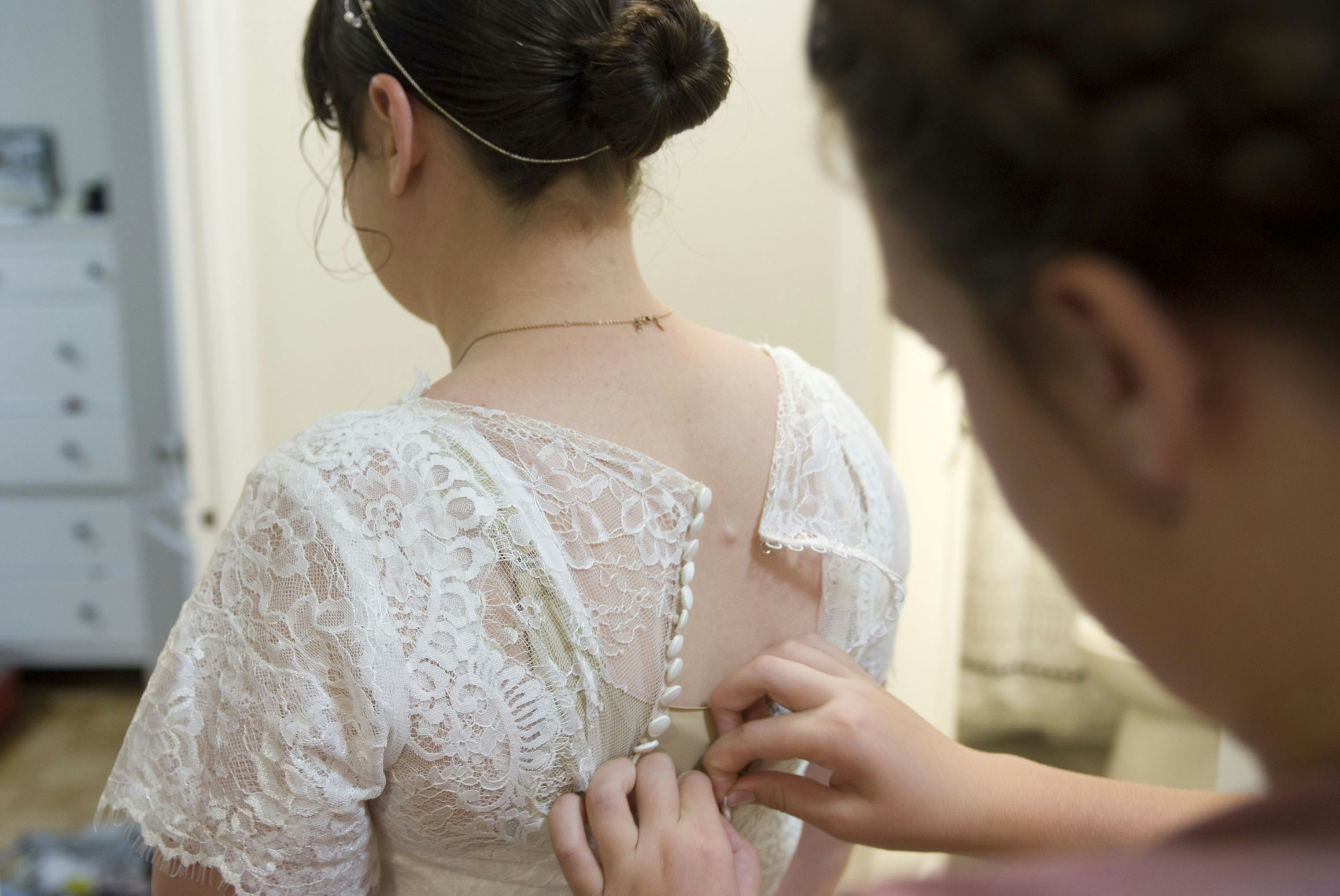 tailor pinning a dress on a customer - emergency dress alterations