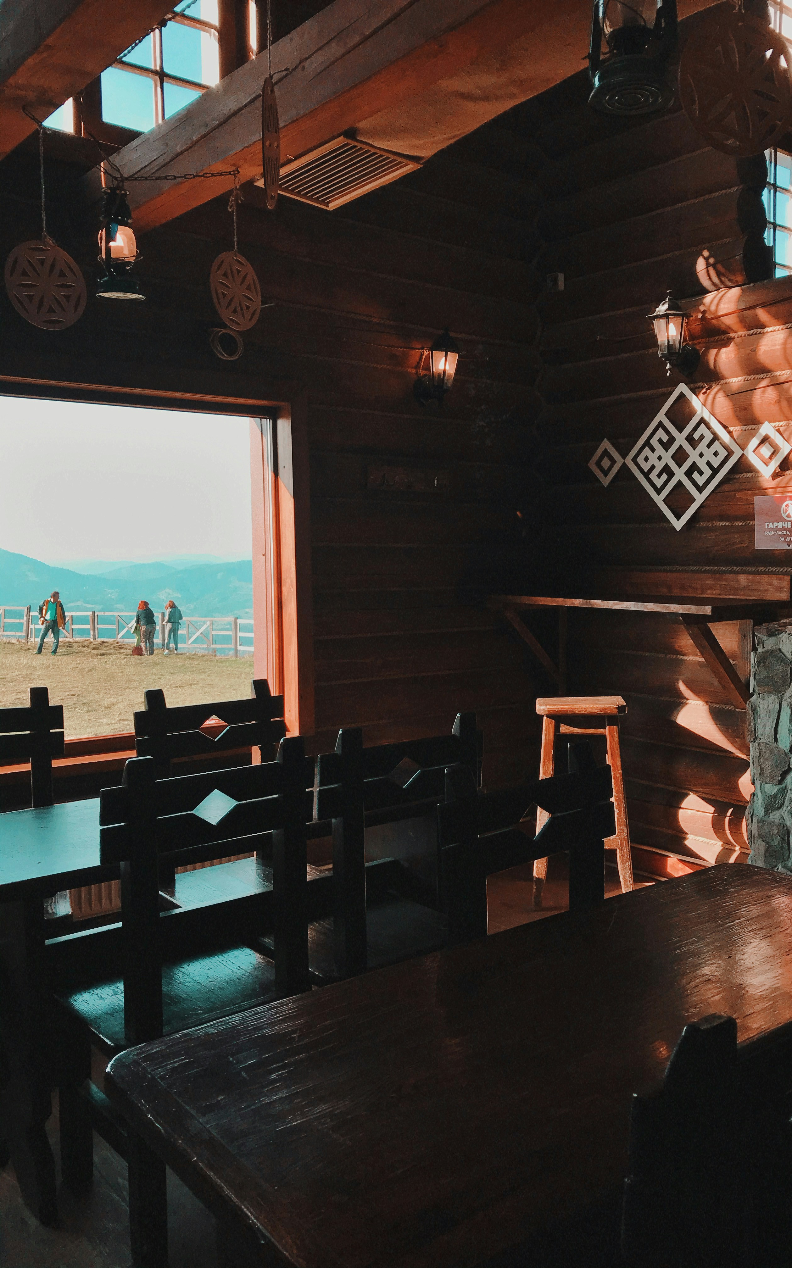 Cozy mountain café with wooden tables and travelers eating breakfast with river view