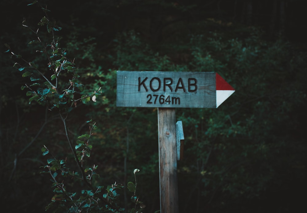 a wooden sign with a red and white arrow pointing to korab