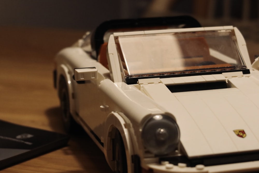 a white toy car sitting on top of a wooden table