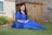 a woman in a blue dress sitting on the grass