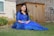 a woman in a blue dress sitting on the grass