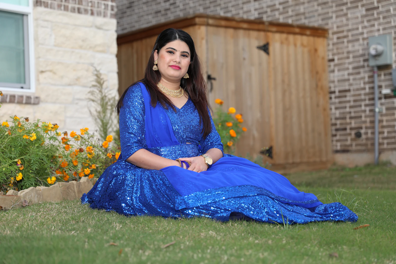 Woman sitting on grass in a cobalt blue sequin gown