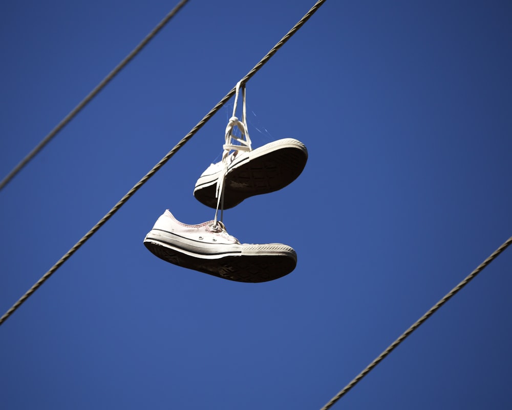 a pair of tennis shoes hanging from a wire