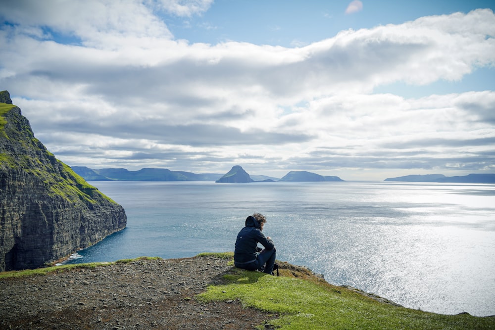 a person sitting on a cliff overlooking a body of water