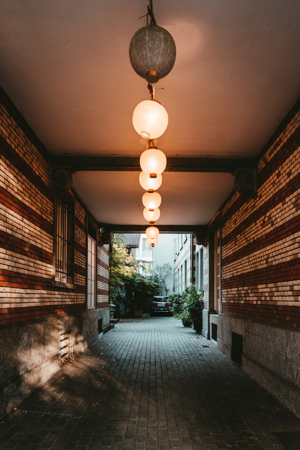 a hallway with a brick wall and several lights hanging from the ceiling