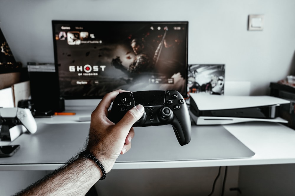 Una persona sosteniendo un controlador de videojuegos frente a un televisor
