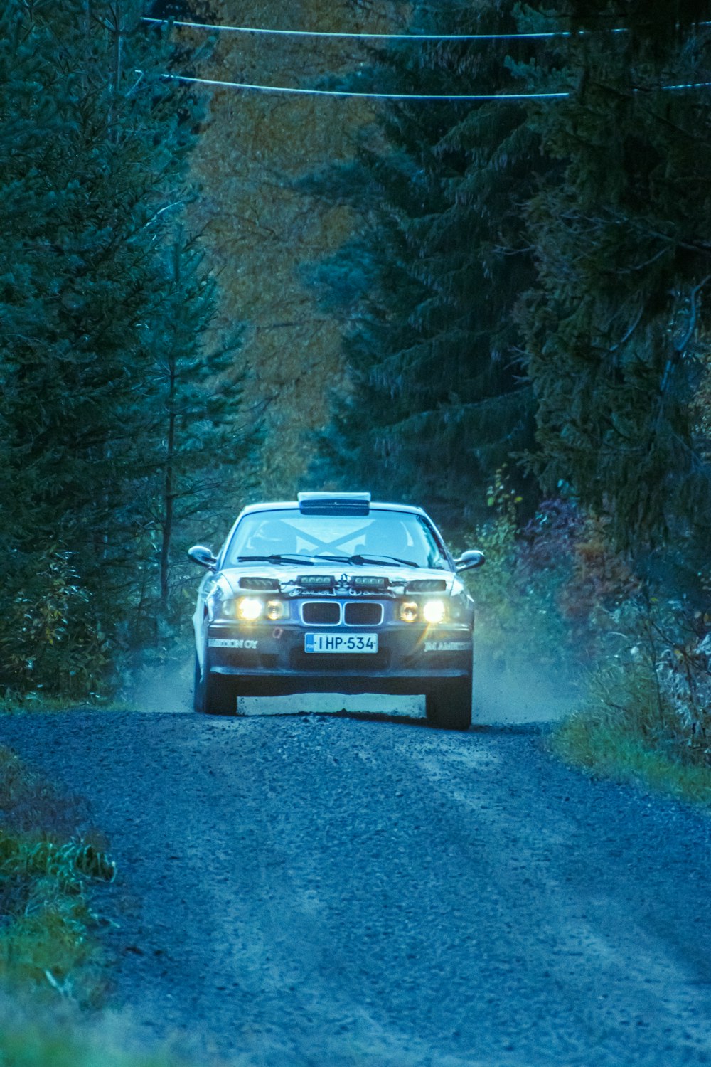 a car driving down a dirt road in the woods