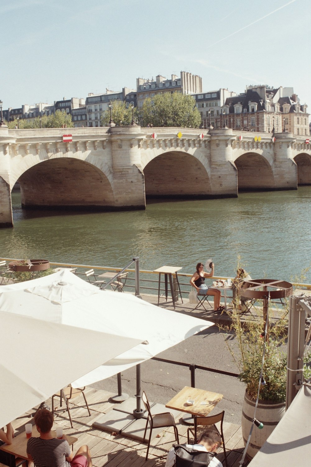 a group of people sitting at tables next to a river