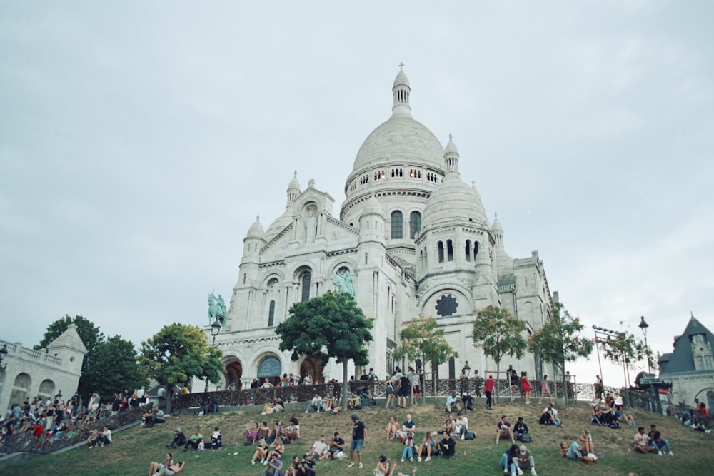 a group of people sitting on the grass in front of a building