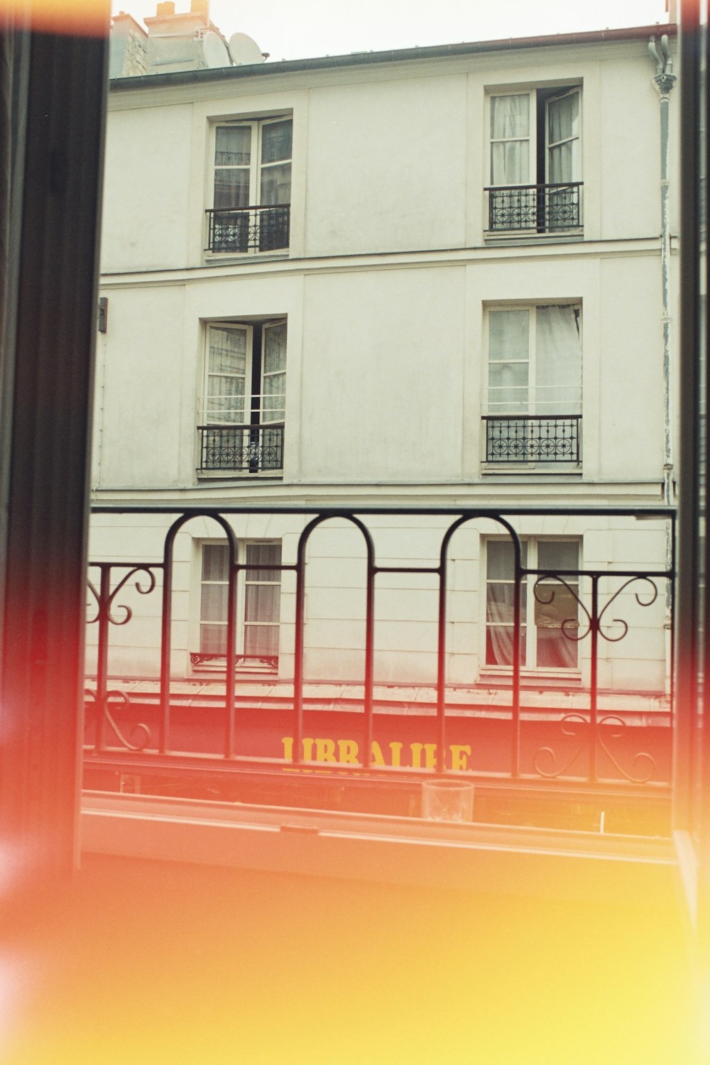 a red train traveling past a tall white building