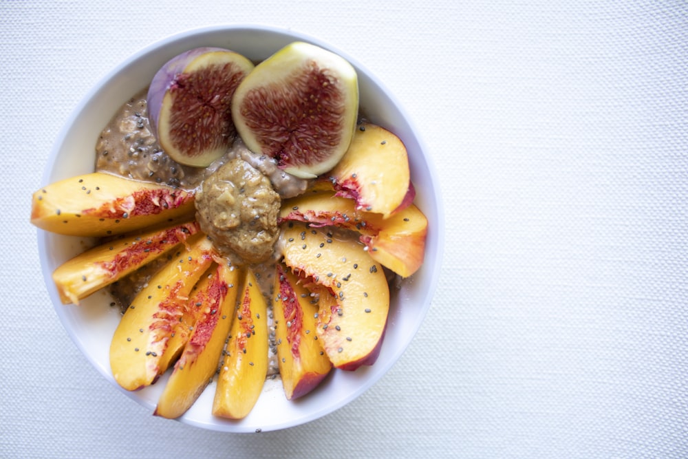 a white bowl filled with sliced fruit on top of a table