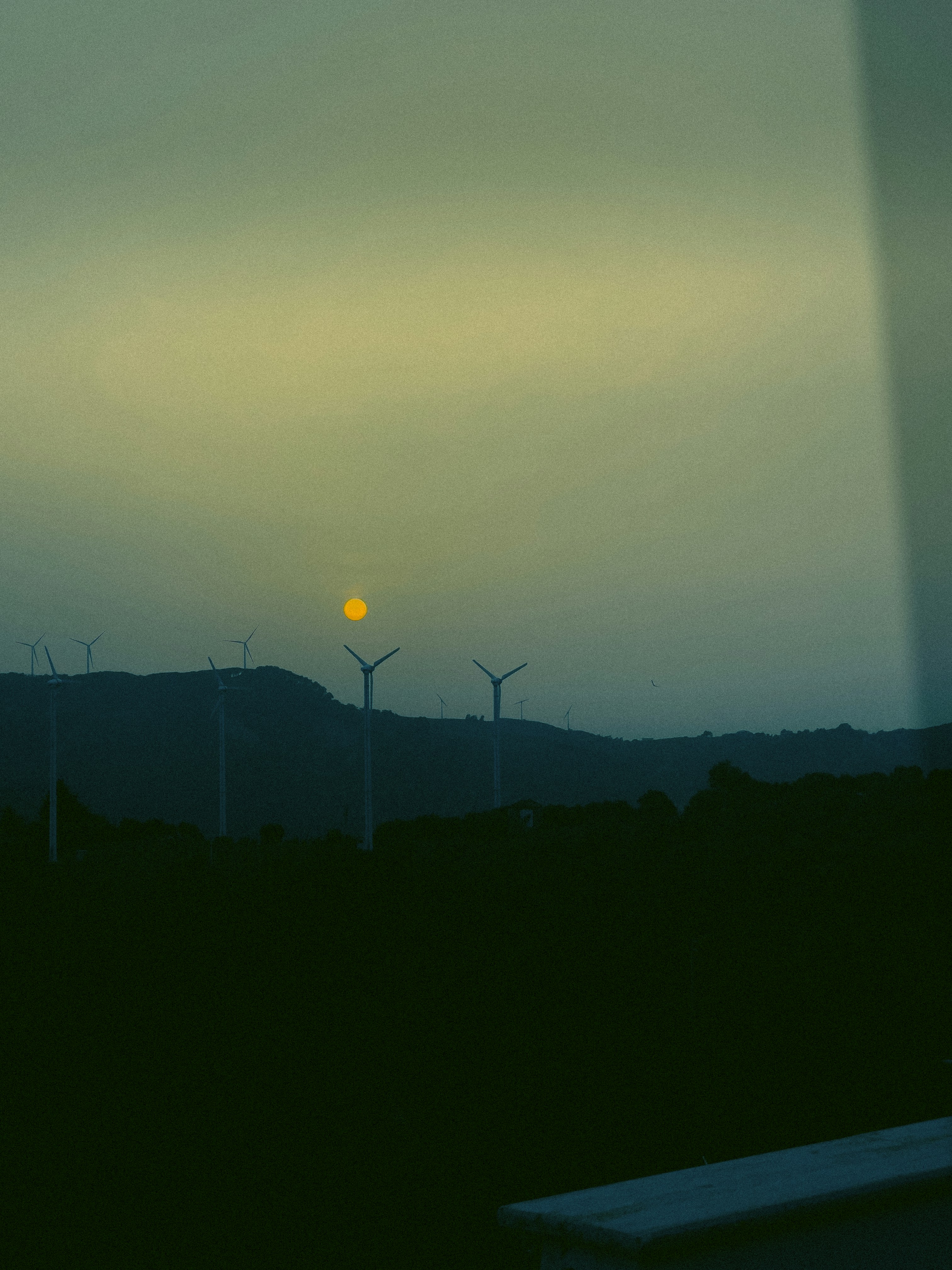 Die Sonne geht hinter einer Reihe von Windmühlen unter