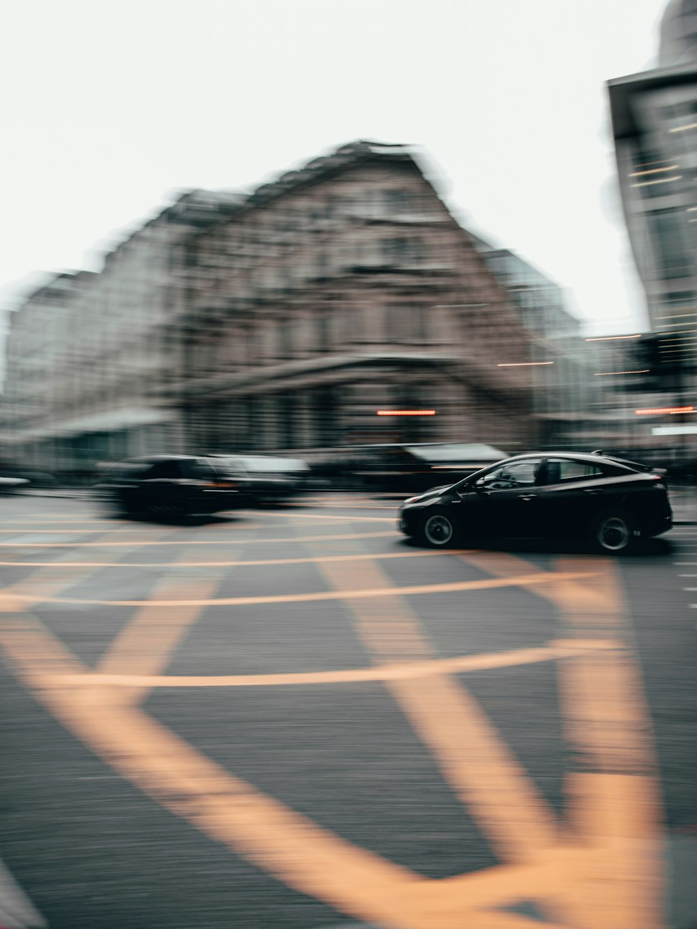 a black car driving down a street next to tall buildings