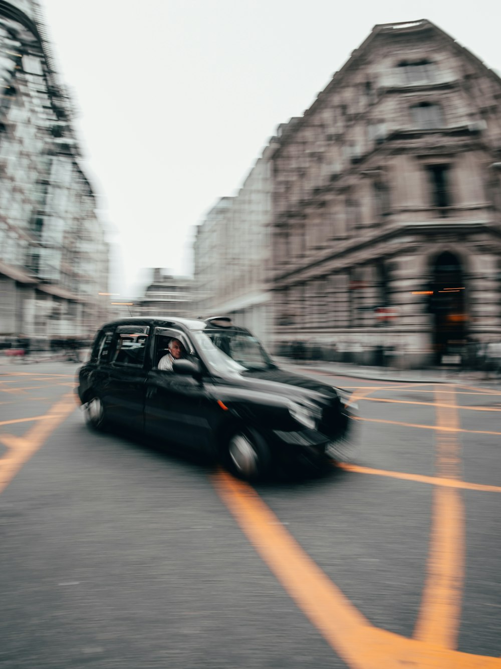 a black car driving down a street next to tall buildings