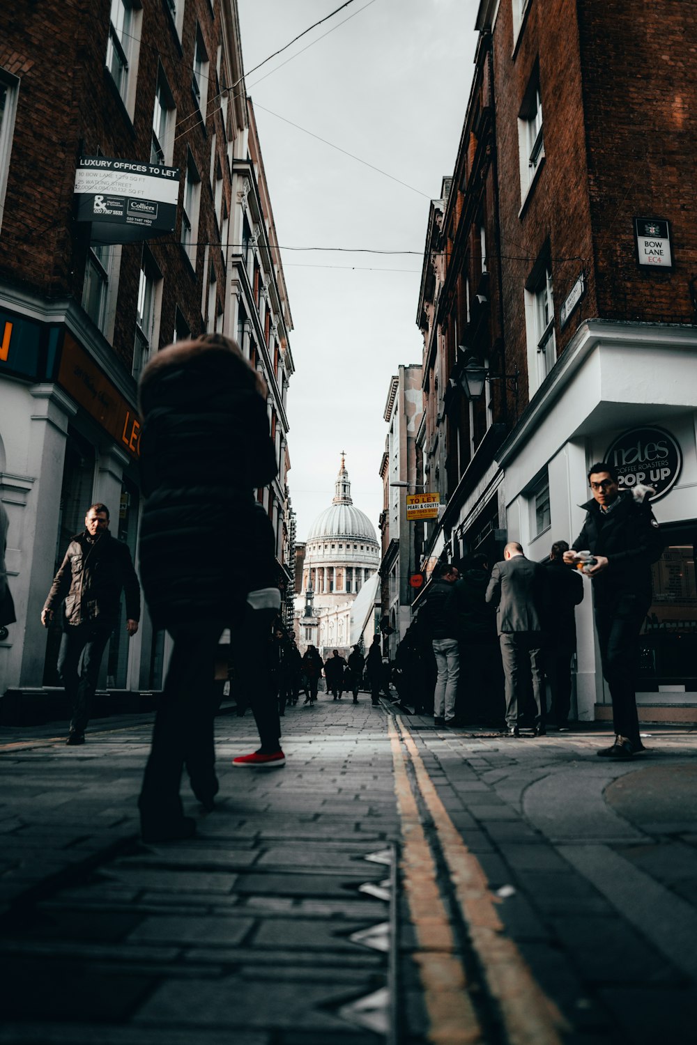 a group of people walking down a street next to tall buildings