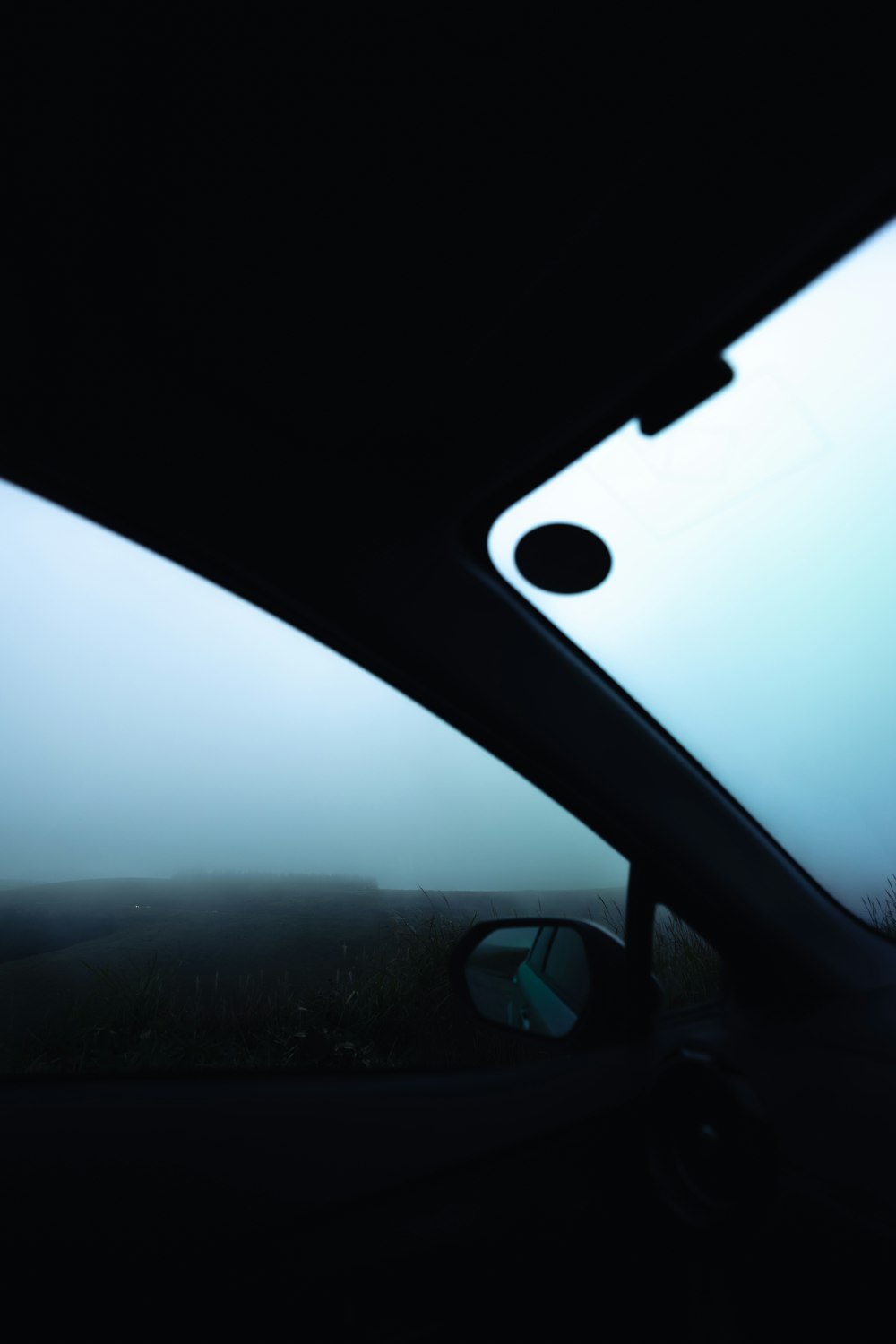 a rear view mirror of a car on a foggy day
