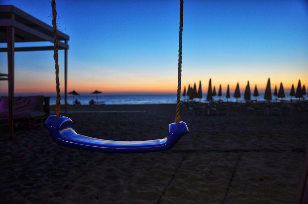 a blue swing sitting on top of a sandy beach