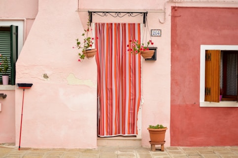 a pink house with a red and white striped curtain