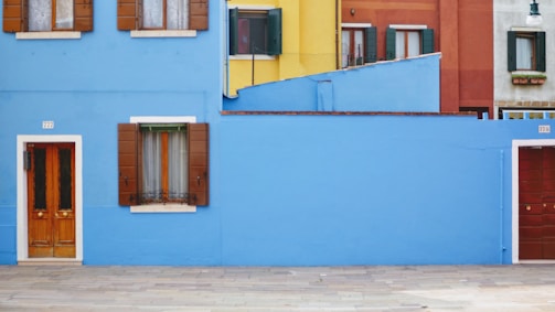 a blue building with two red doors and windows