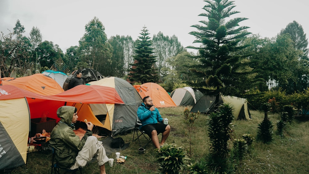 a group of people sitting around tents in a field