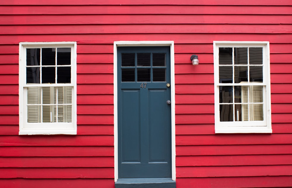 a red building with two windows and a blue door