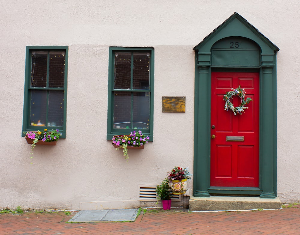 a red door with two green windows and a bench in front of it