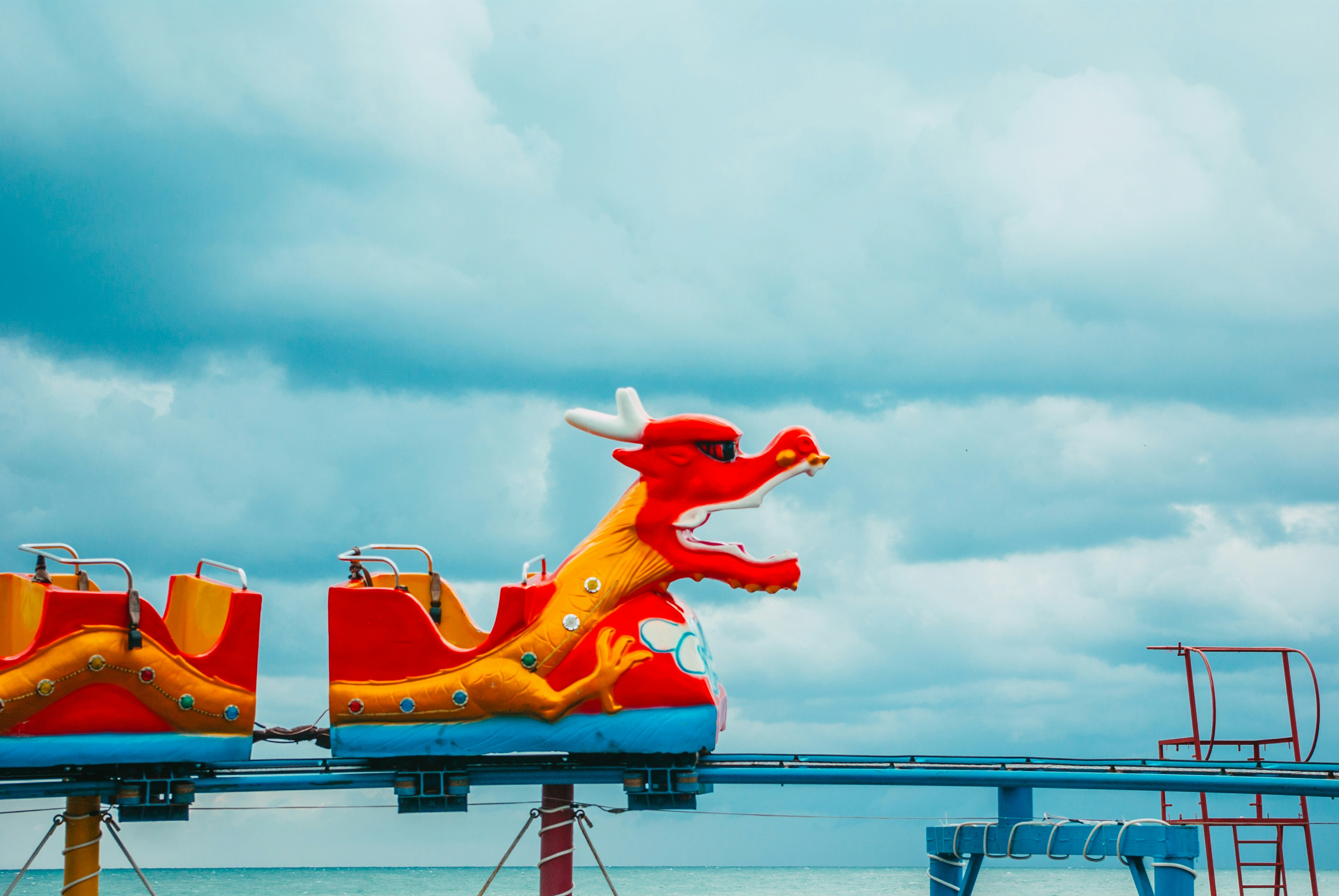 a red and yellow dragon roller coaster on a cloudy day