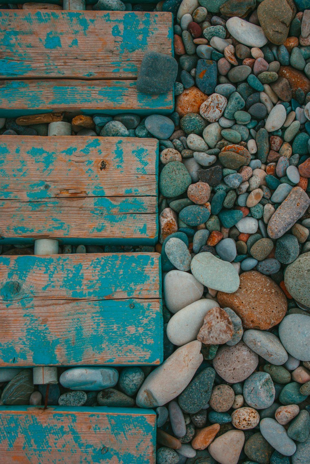 a pile of rocks and wooden benches sitting on top of a beach