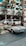 A classic white convertible Mercedes-Benz is parked on a paved driveway in front of a modern hotel with a sign reading 'Jumeirah'. The background features palm trees and a glass building facade, with other parked cars visible nearby.