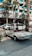 A classic white convertible Mercedes-Benz is parked on a paved driveway in front of a modern hotel with a sign reading 'Jumeirah'. The background features palm trees and a glass building facade, with other parked cars visible nearby.
