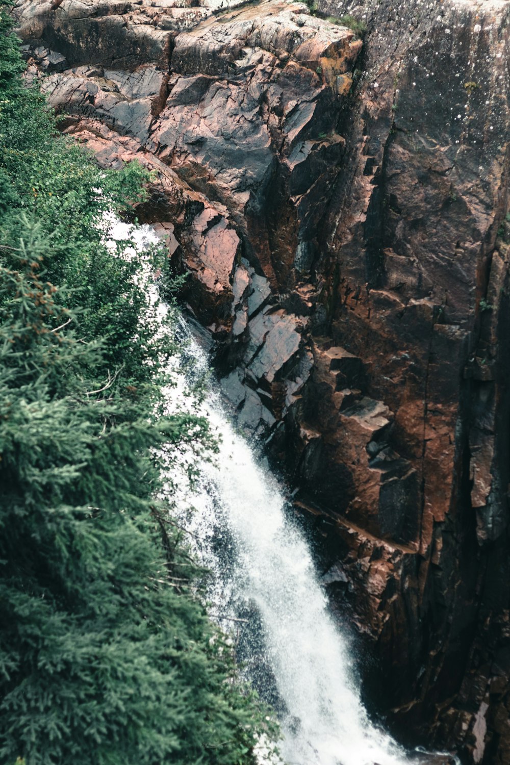 um homem de pé no topo de um penhasco ao lado de uma cachoeira
