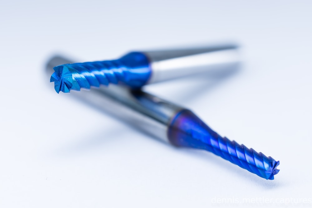 a close up of two blue toothbrushes on a white surface